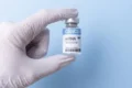 Cientista analisa frasco de vacina mRNA personalizada contra melanoma em laboratório oncológico
