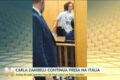 Carla Zambelli em tribunal italiano com bandeiras do Brasil e Itália ao fundo, simbolizando disputa de extradição