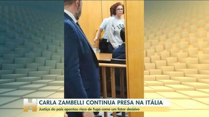 Carla Zambelli em tribunal italiano com bandeiras do Brasil e Itália ao fundo, simbolizando disputa de extradição