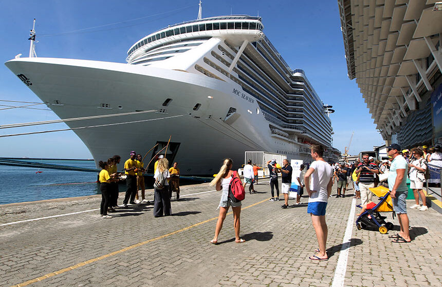 Navio de cruzeiro atracado em porto brasileiro com passageiros embarcando, temporada 2026/2027